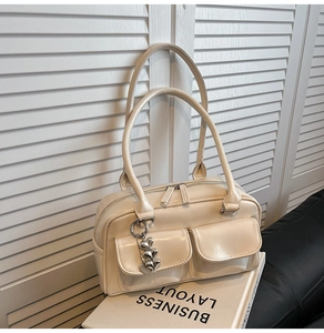 Detail of cream white faux leather tote bag with heart charms and front pockets