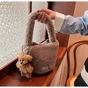 Detailed shot of brown plush bucket bag with cute bear pendant and Clear K label