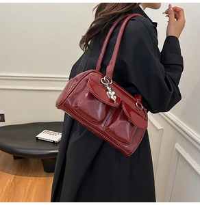 Detailed close-up of glossy wine red patent leather shoulder bag with heart charm