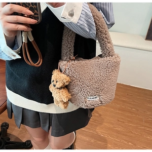 Close-up of fluffy brown plush bucket bag with cute bear charm and woven logo tag