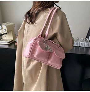 Detail showing glossy pink pocket bag with a silver teddy bear pendant on shoulder