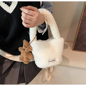 Close-up of fluffy white faux fur bucket bag with a cute brown bear charm detail