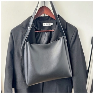 Minimalist black tote bag hanging on a hanger, showcasing large capacity and smooth matte finish