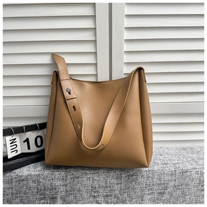 Detail of adjustable wide shoulder strap with metal buckle on camel faux leather tote