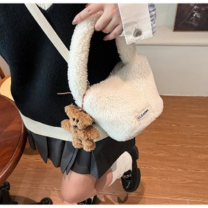 Close-up of white plush bucket bag with cute brown bear charm and brand logo tag