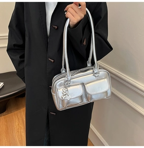 Detail of silver metallic shoulder bag with double pockets and heart charm pendant