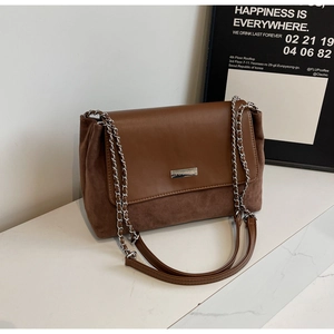 Detail of a brown shoulder bag with mixed faux leather and suede textures and silver chain