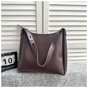 Detailed macro view showing dark brown leather texture and adjustable strap of the hobo bag