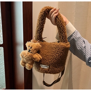 Detail of plush brown bucket bag with fuzzy bear charm and woven CLEAR logo tag