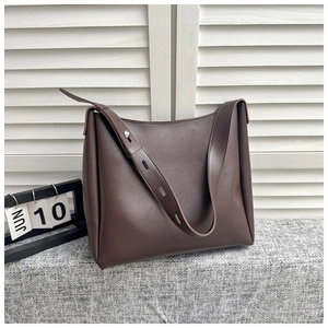 Detail of adjustable silver buckle and strap on a brown leather bucket tote bag