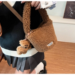 Close-up of brown plush bucket bag with soft faux fur texture and cute bear pendant