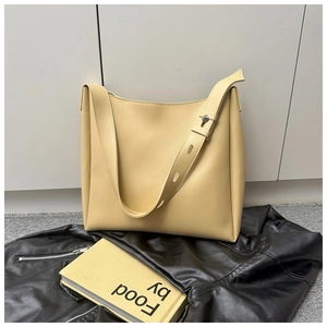 Detail of adjustable wide strap and metal rivet on cream yellow faux leather tote bag