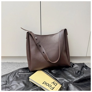 Close-up of a large dark brown leather tote bag with an adjustable wide shoulder strap