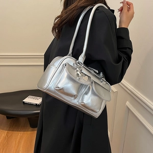 Metallic silver shoulder bag with multiple pockets and heart charms on a black coat