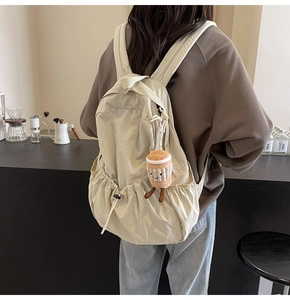 Detail of beige canvas backpack with a cute coffee cup plush charm in a cafe setting