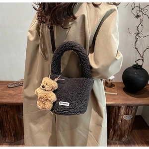 Detail view of dark grey plush bucket bag with curly faux fur texture and a cute bear charm