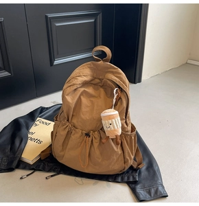Detail of khaki casual nylon backpack with cute plush coffee cup charm on leather jacket