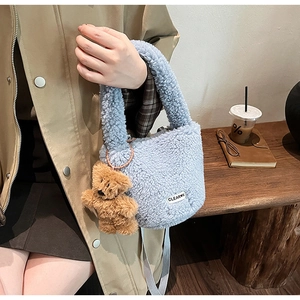 Detail view of light blue plush bucket bag with teddy bear charm and grey strap