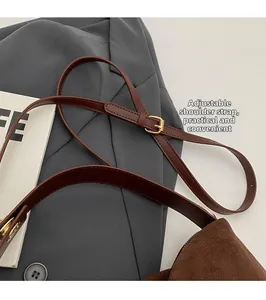 Détail de la bandoulière réglable avec boucle dorée sur un sac Boston en daim