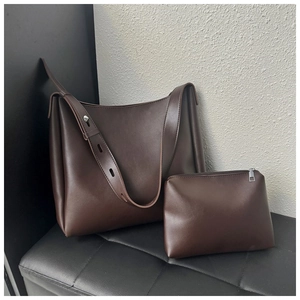 Detail view of coffee brown leather tote and matching zipper pouch on minimalist bench