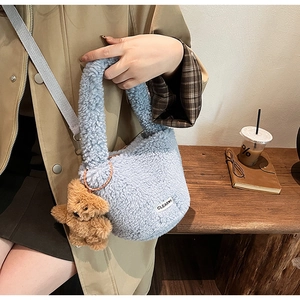 Detail of light blue faux shearling bucket bag with a brown plush bear and coffee scene