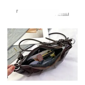 Macro view of dark brown patent leather shoulder bag showing spacious interior compartment