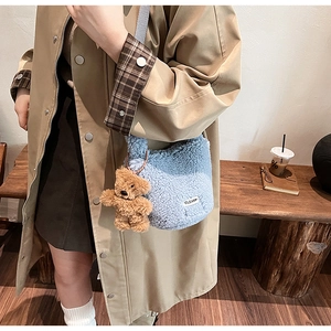 Detail of light blue fuzzy fleece bucket bag with a cute brown bear doll keychain