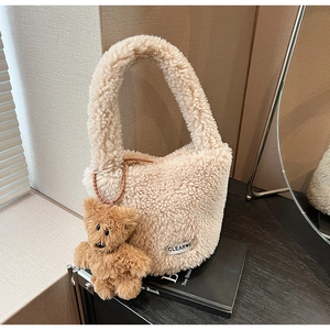 Detail of beige faux shearling bucket bag featuring brand label and cute teddy bear charm