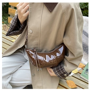 Close-up of the pleated dark brown glossy croissant bag with silver zipper detail
