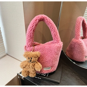 Detail of pink plush bucket bag with fuzzy texture and cute teddy bear charm accessory