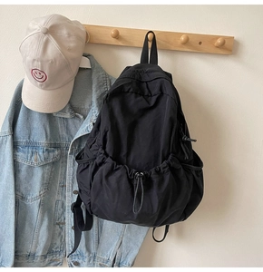 Detailed view of lightweight black nylon backpack hanging on a rack with outdoor gear