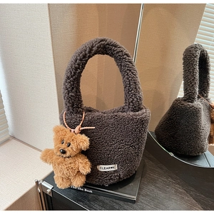Detail of plush brown bucket bag with soft texture and cute bear pendant charm
