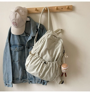 Detail of light beige casual backpack featuring functional side drawstring pocket design
