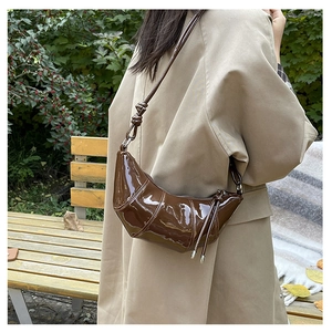 Detail of dark brown patent leather dumpling bag with knotted shoulder strap