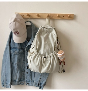 Detail view of cream nylon backpack with drawstring pocket and cute coffee cup charm