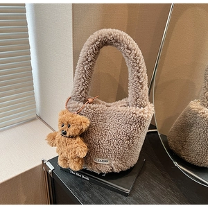 Detailed view of brown plush bucket bag with lamb wool texture and cute bear charm