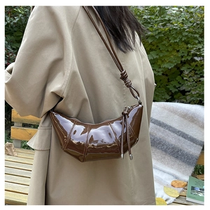 Street style shot of dark brown glossy patent leather croissant bag with pleated texture