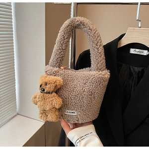 Detailed macro of plush light brown faux fur bucket bag featuring a cute teddy bear charm