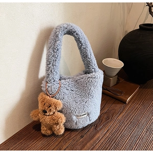 Detail of blue plush bucket bag with fuzzy texture and cute brown teddy bear keychain charm