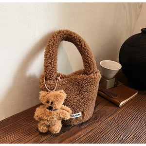 Detailed texture of brown plush bucket bag with cute bear charm and woven logo tag