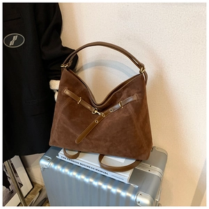 Close-up detail of dark brown suede hobo bag texture with golden hardware and belt decor