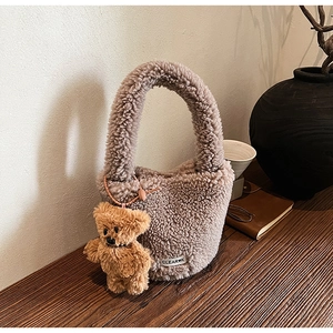 Detail of soft brown plush bucket bag with teddy texture, clear k label and bear charm