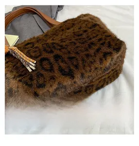 Detail of leopard print faux fur tote bag with brown leather strap and tassel charm