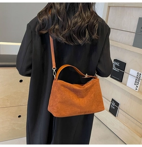 Gros plan du sac Boston en daim marron avec boucles dorées et bandoulière réglable