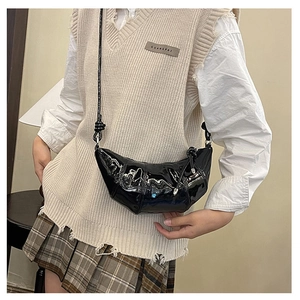 Detail view of black patent leather croissant bag with stylish pleated texture and slim strap