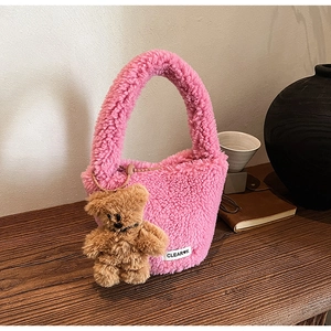 Detail of pink plush bucket bag featuring soft sherpa texture and cute teddy bear charm