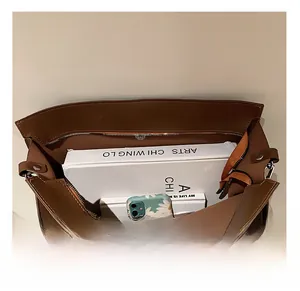 Vista macro dell'interno spazioso di questa borsa tote in pelle marrone con libri e cellulare
