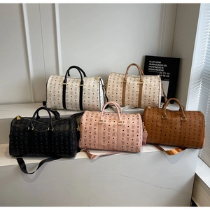 Five monogrammed travel duffel bags in various colors displayed on a marble surface