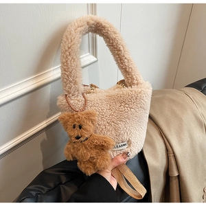 Detailed macro of beige plush bucket bag with cute brown bear charm and logo tag