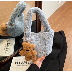 Detail of light blue faux fur bucket bag with cute brown teddy bear charm and brand label